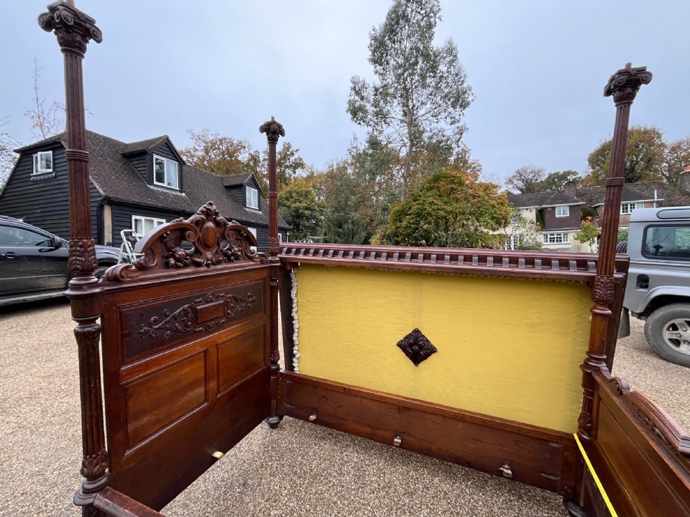 A dark carved oak four poster bed featuring turned columns, an ornate carved headboard, and a gold fabric-lined canopy. View VII