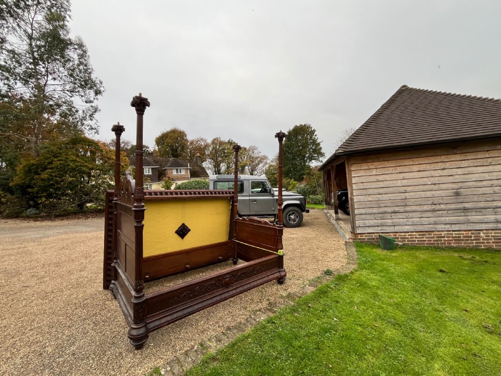 A dark carved oak four poster bed featuring turned columns, an ornate carved headboard, and a gold fabric-lined canopy. View VIII