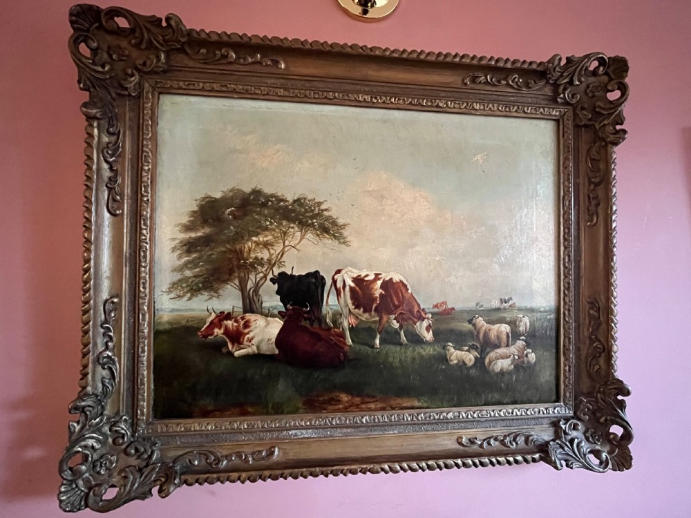 A Victorian oil painting on canvas depicting cattle and sheep resting in a field, presented within an ornate carved gilt moulding frame. View V