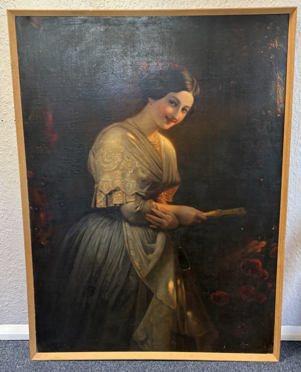 A nineteenth-century oil painting on canvas depicting a smiling woman in a lace shawl holding a fan against a dark background.