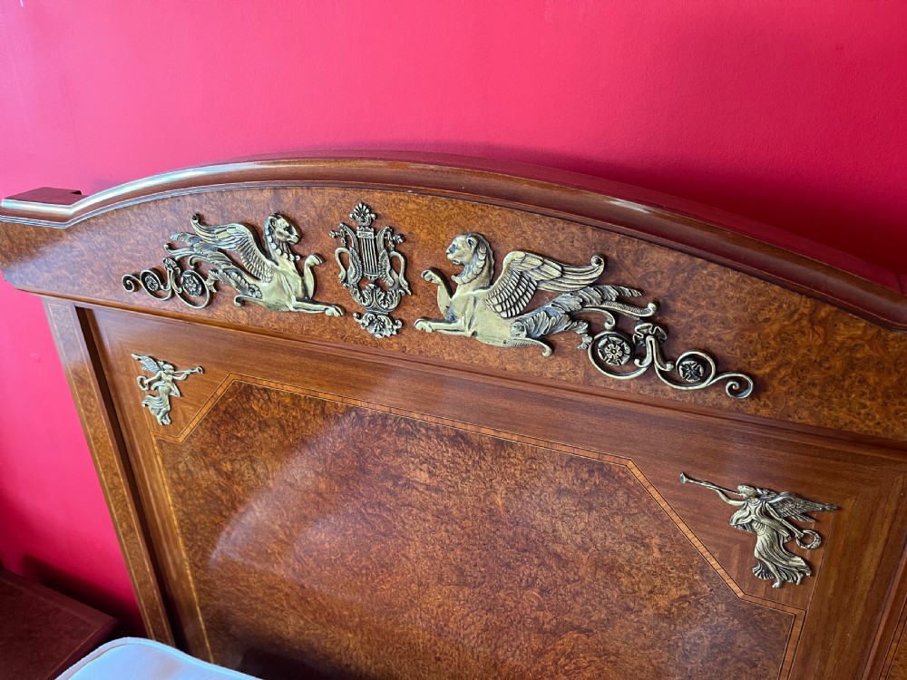 A pair of late nineteenth-century French Empire single sleigh beds crafted from warm brown polished wood with ornamental gilt mounts on the headboards and footboards. View II