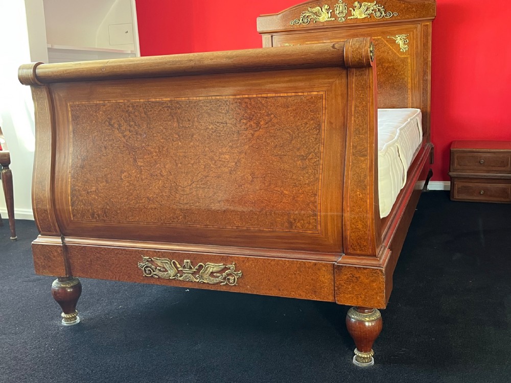 A pair of late nineteenth-century French Empire single sleigh beds crafted from warm brown polished wood with ornamental gilt mounts on the headboards and footboards. View III