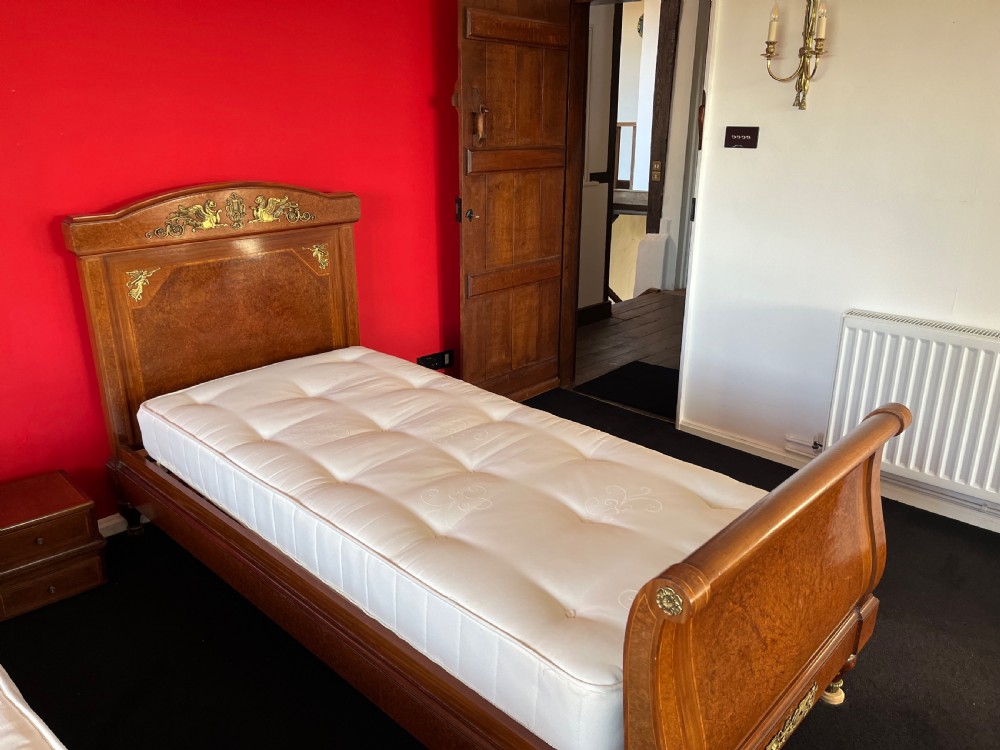 A pair of late nineteenth-century French Empire single sleigh beds crafted from warm brown polished wood with ornamental gilt mounts on the headboards and footboards. View IV