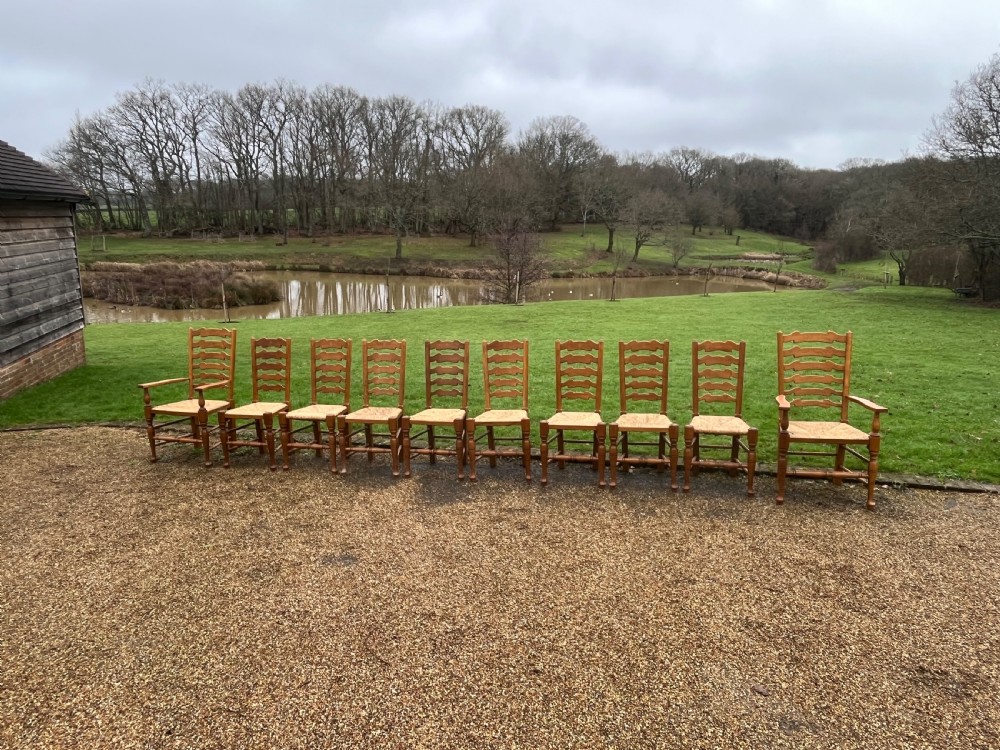 A set of ten antique oak ladder back dining chairs featuring woven rush seats and turned legs, comprising eight side chairs and two carver armchairs. View II
