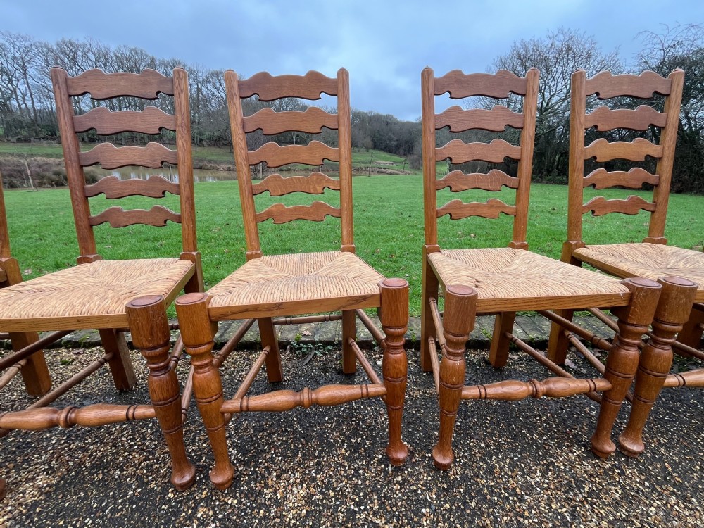 A set of ten antique oak ladder back dining chairs featuring woven rush seats and turned legs, comprising eight side chairs and two carver armchairs. View V