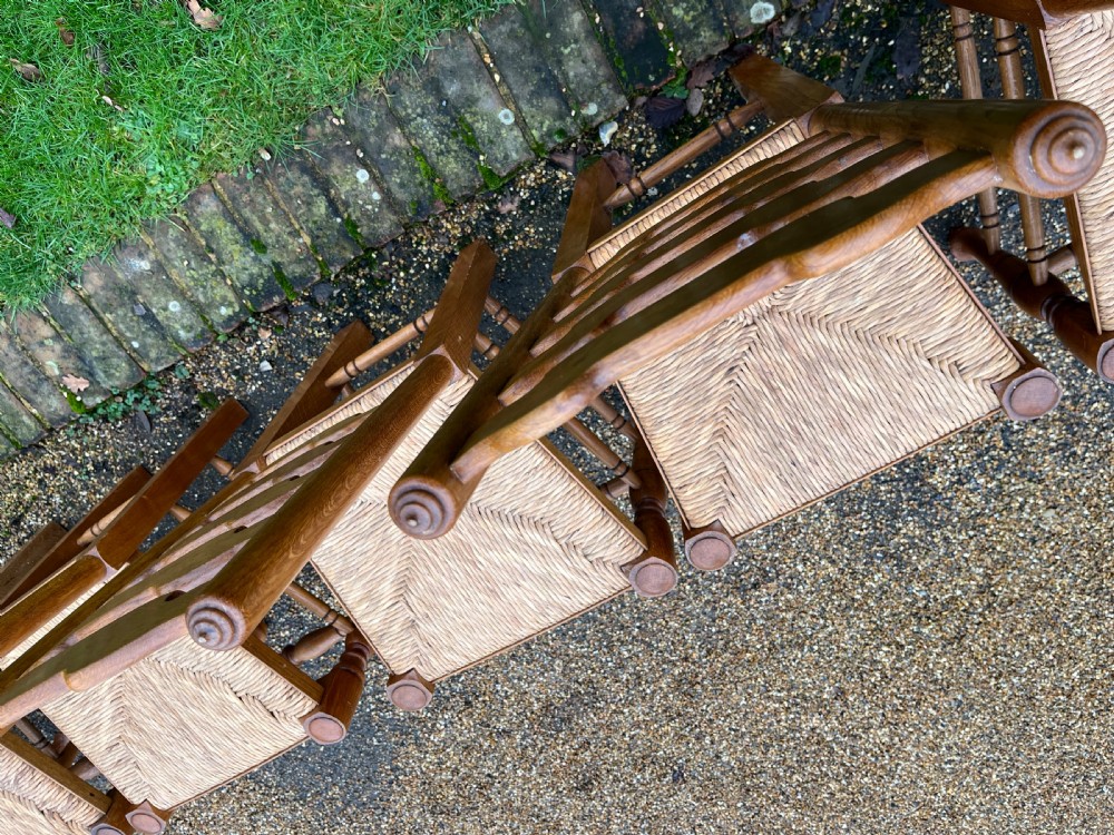 A set of ten antique oak ladder back dining chairs featuring woven rush seats and turned legs, comprising eight side chairs and two carver armchairs. View VI