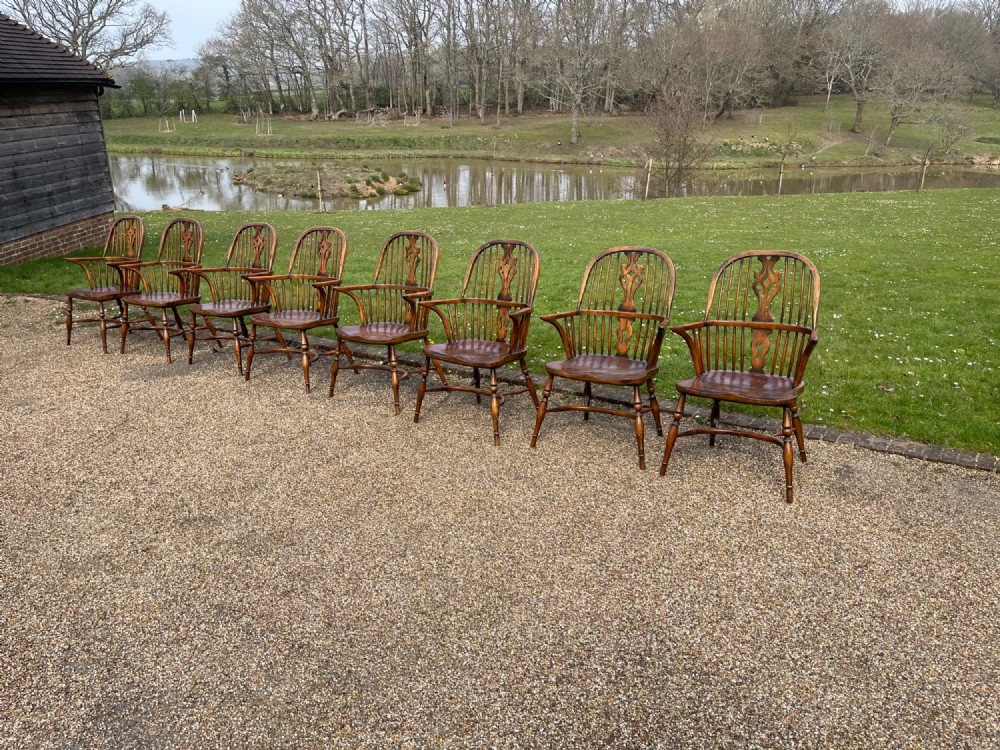 A set of eight matching wooden Windsor armchairs featuring pierced splats, turned spindles, curved armrests, and turned legs. View II