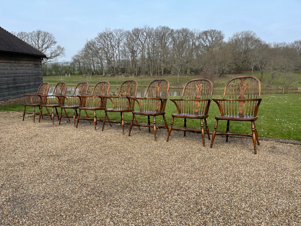 A set of eight matching wooden Windsor armchairs featuring pierced splats, turned spindles, curved armrests, and turned legs. View III