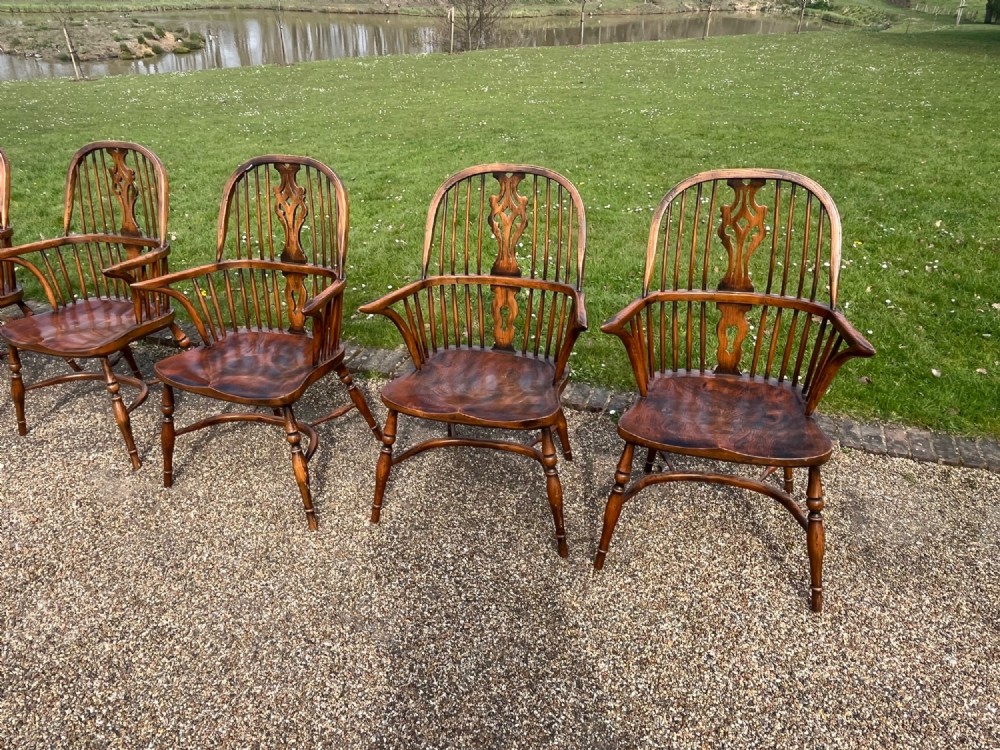 A set of eight matching wooden Windsor armchairs featuring pierced splats, turned spindles, curved armrests, and turned legs. View IV