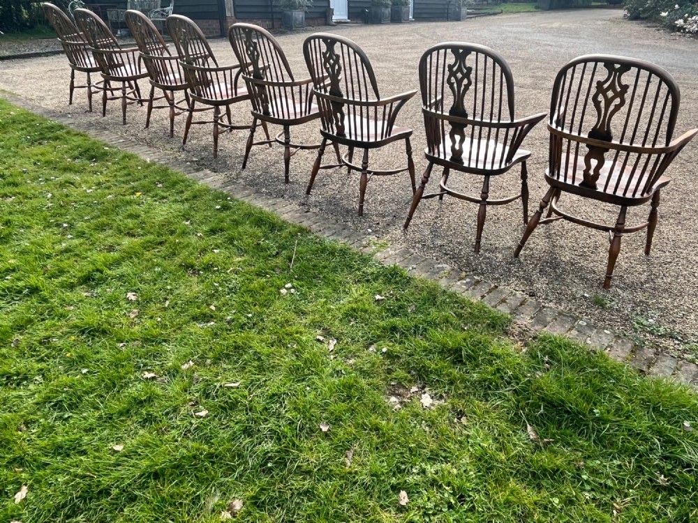 A set of eight matching wooden Windsor armchairs featuring pierced splats, turned spindles, curved armrests, and turned legs. View V