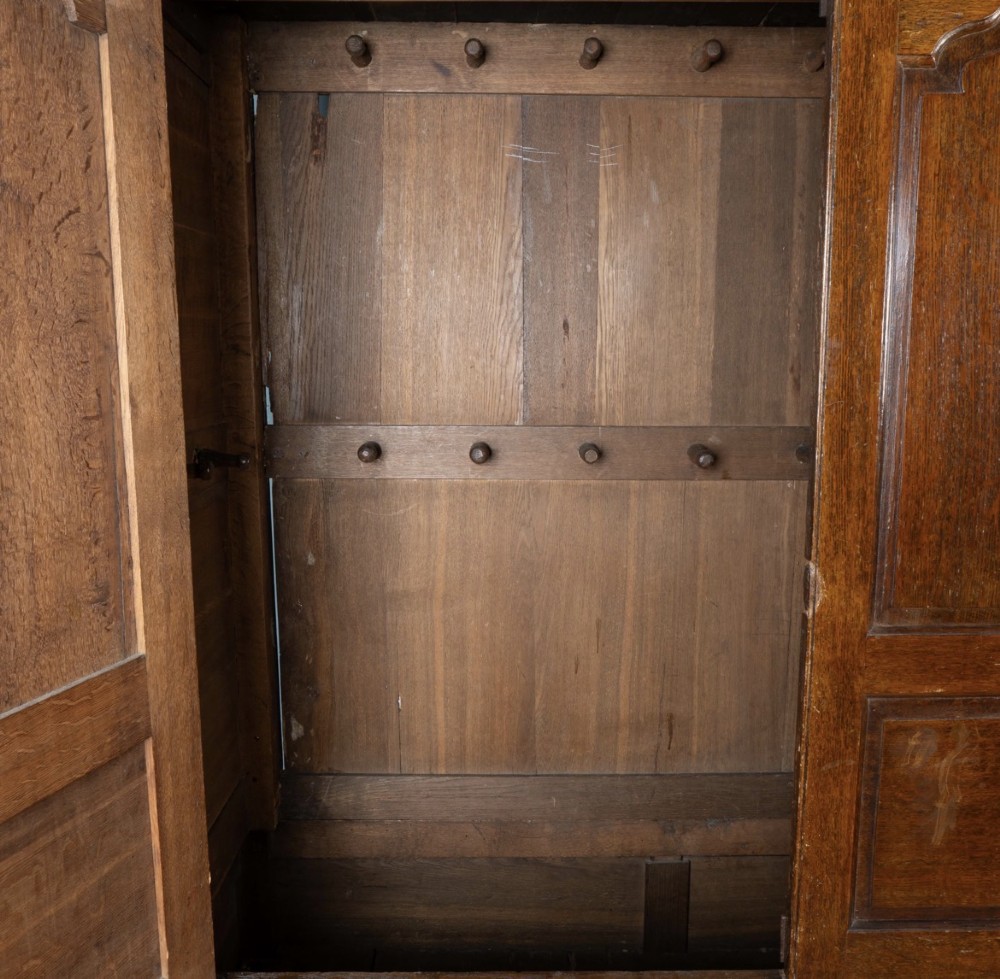 A large 18th-century Georgian dark oak press cupboard featuring an upper three-door cabinet with fielded panels over a lower base with nine brass-handled drawers. View II