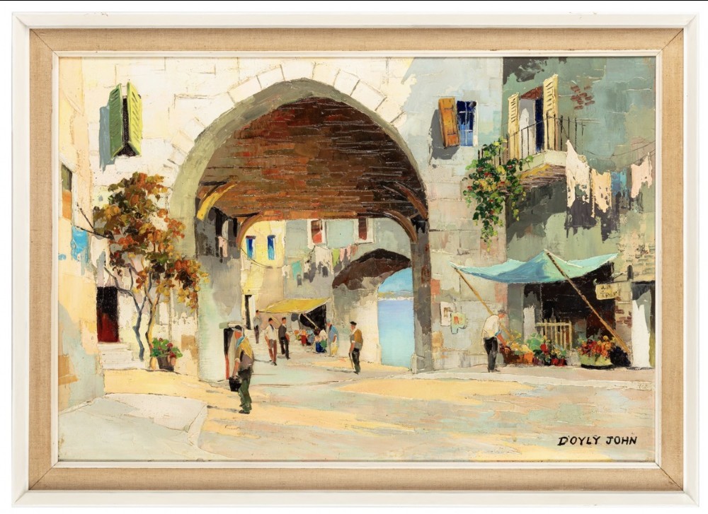 An oil painting depicting a sunlit Mediterranean architectural archway and village street scene with figures, set within a cream wood frame.