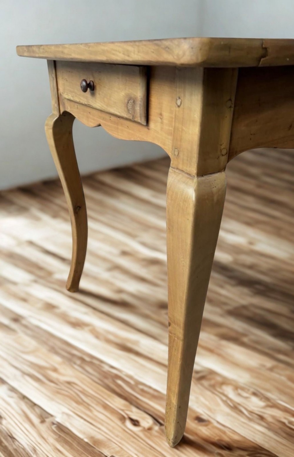 A late nineteenth-century French cherrywood dining table featuring curved cabriolet legs, a planked top, and an apron drawer. View III