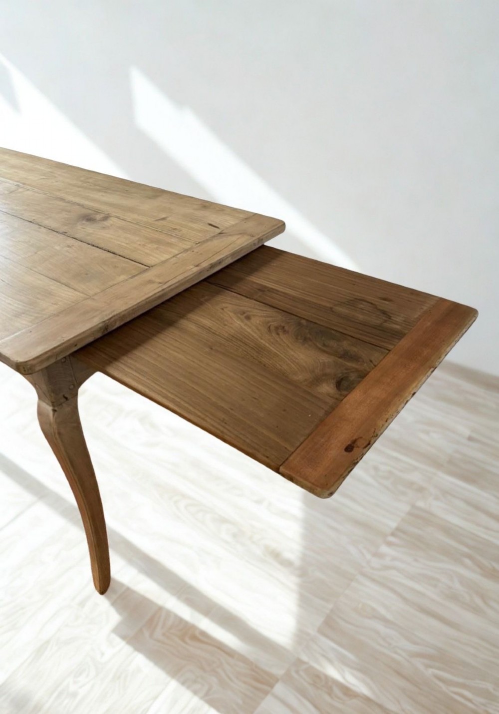 A late nineteenth-century French cherrywood dining table featuring curved cabriolet legs, a planked top, and an apron drawer. View IV