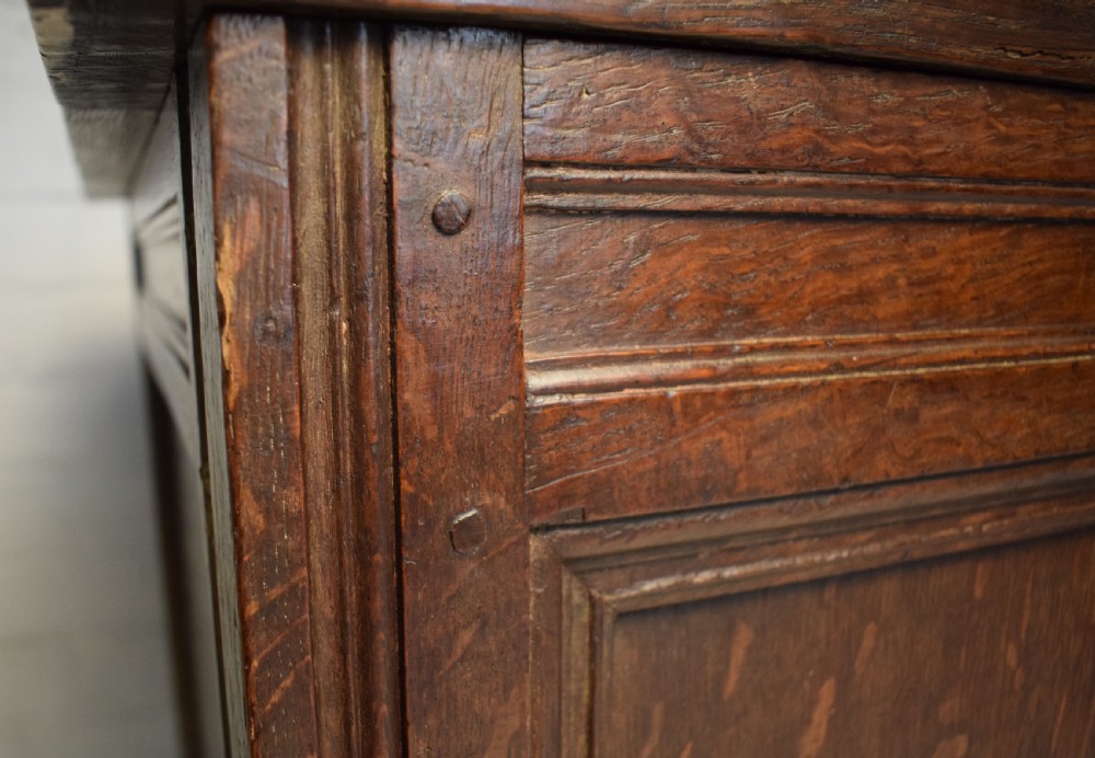 A dark oak panelled storage coffer with four inset front panels, a flat hinged lid, and sturdy stile feet. View III
