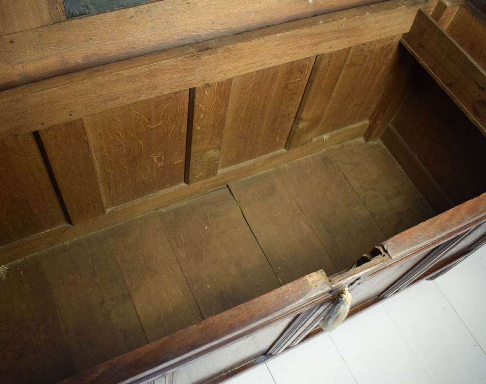 A dark oak panelled storage coffer with four inset front panels, a flat hinged lid, and sturdy stile feet. View V