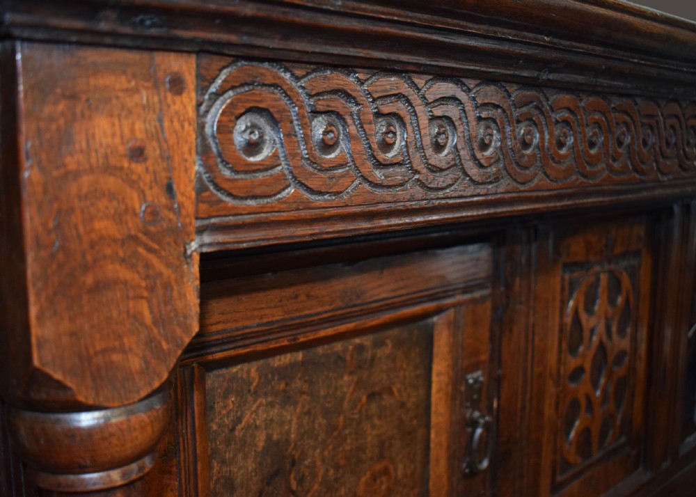 A three-tier dark oak Welsh tridarn dresser featuring carved frieze panels, baluster supports, and lower cupboard doors. View III