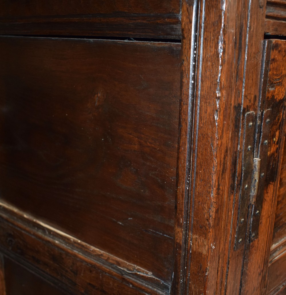 A three-tier dark oak Welsh tridarn dresser featuring carved frieze panels, baluster supports, and lower cupboard doors. View V