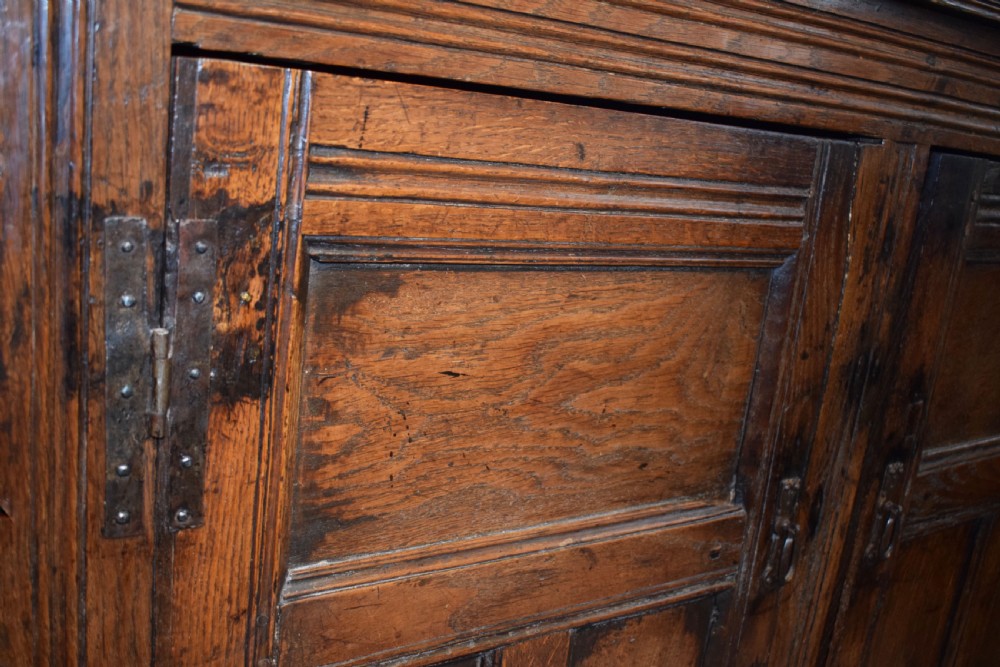 A three-tier dark oak Welsh tridarn dresser featuring carved frieze panels, baluster supports, and lower cupboard doors. View VI
