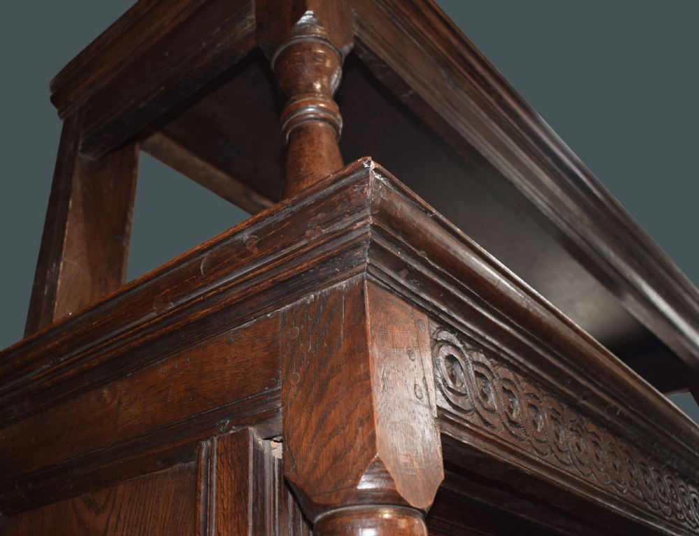 A three-tier dark oak Welsh tridarn dresser featuring carved frieze panels, baluster supports, and lower cupboard doors. View VIII