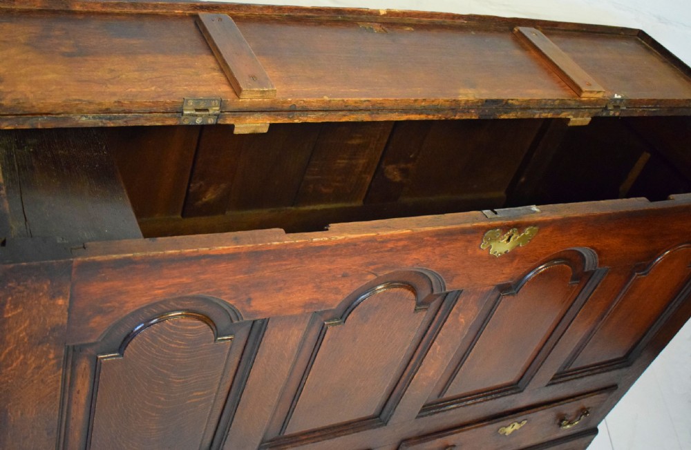 A dark oak antique mule chest featuring four arched fielded panels, two lower drawers with brass drop handles, and bracket feet. View IV