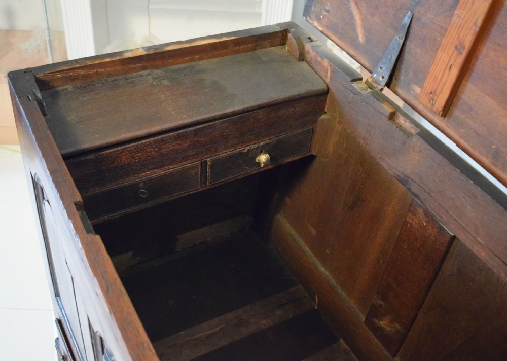 A dark oak antique mule chest featuring four arched fielded panels, two lower drawers with brass drop handles, and bracket feet. View V