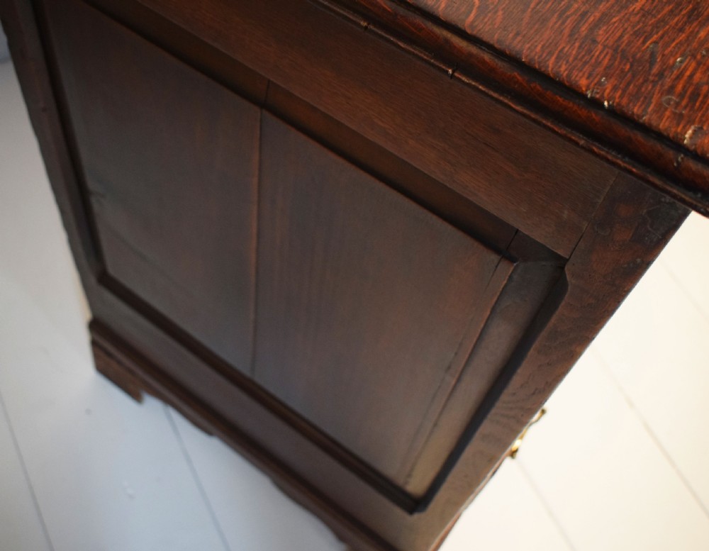 A dark oak antique mule chest featuring four arched fielded panels, two lower drawers with brass drop handles, and bracket feet. View VIII