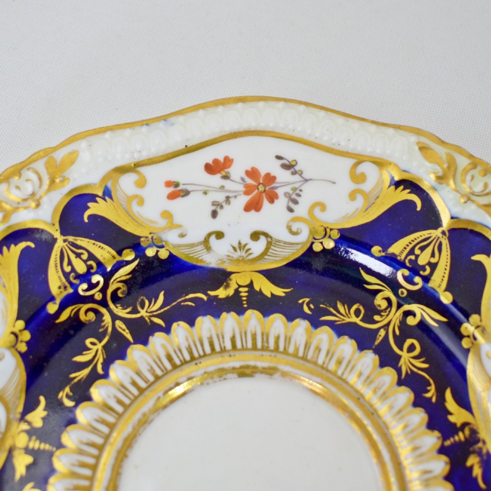 An antique porcelain teacup and saucer decorated with deep cobalt blue panels, floral hand-painted vignettes, and gold gilding. View V