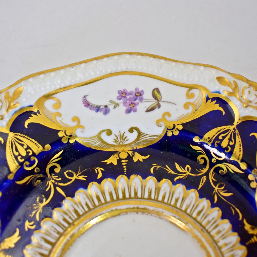 An antique porcelain teacup and saucer decorated with deep cobalt blue panels, floral hand-painted vignettes, and gold gilding. View VI