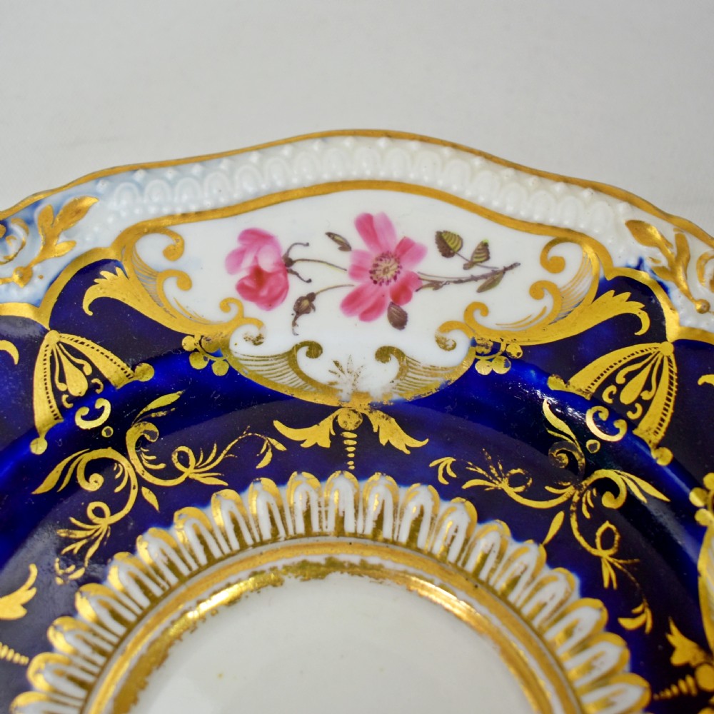 An antique porcelain teacup and saucer decorated with deep cobalt blue panels, floral hand-painted vignettes, and gold gilding. View VII