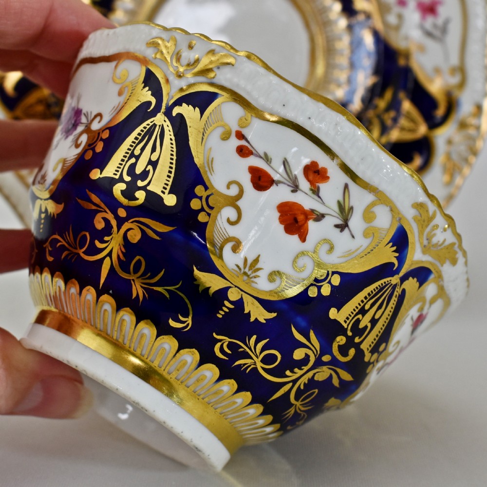 An antique porcelain teacup and saucer decorated with deep cobalt blue panels, floral hand-painted vignettes, and gold gilding. View XII