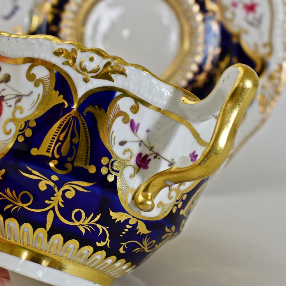 An antique porcelain teacup and saucer decorated with deep cobalt blue panels, floral hand-painted vignettes, and gold gilding. View XV