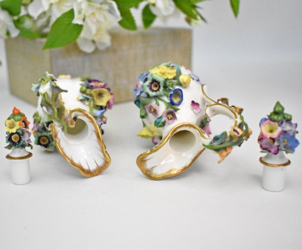 A pair of white Minton porcelain scent bottle ewers featuring applied three-dimensional flowers, gilded scroll handles, and matching floral stoppers. View XIII