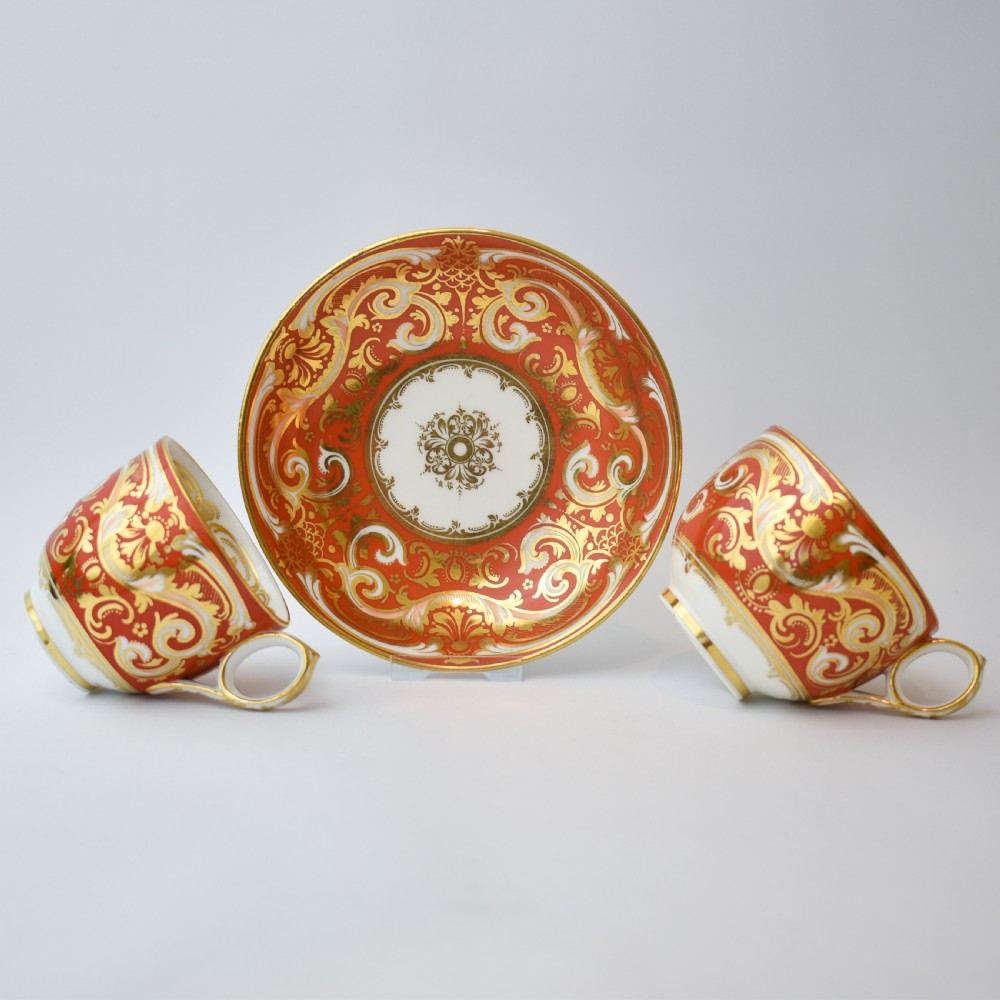 A Victorian Davenport porcelain true trio featuring a stacked tea cup and coffee cup decorated with intricate hand-painted rust red and gold ornamentation resting on a matching saucer. View III