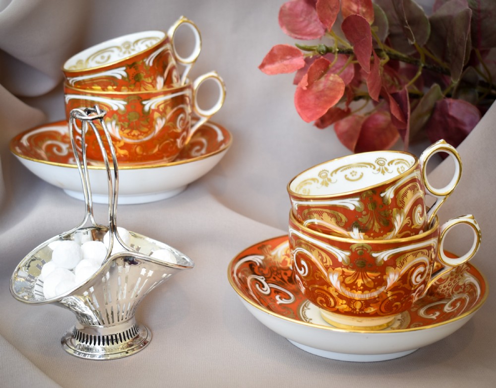 A Victorian Davenport porcelain true trio featuring a stacked tea cup and coffee cup decorated with intricate hand-painted rust red and gold ornamentation resting on a matching saucer. View XI