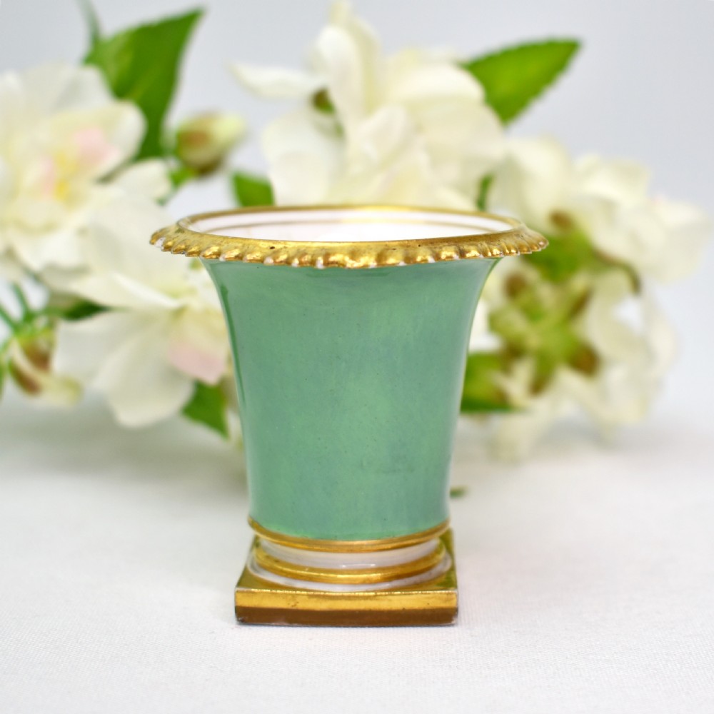 A miniature green Regency porcelain vase featuring a hand-painted exotic bird vignette framed in gold gilding upon a square pedestal base. View III