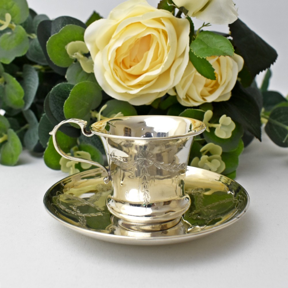 An antique sterling silver cup and saucer set decorated with hand-engraved swag and bow motifs. View V