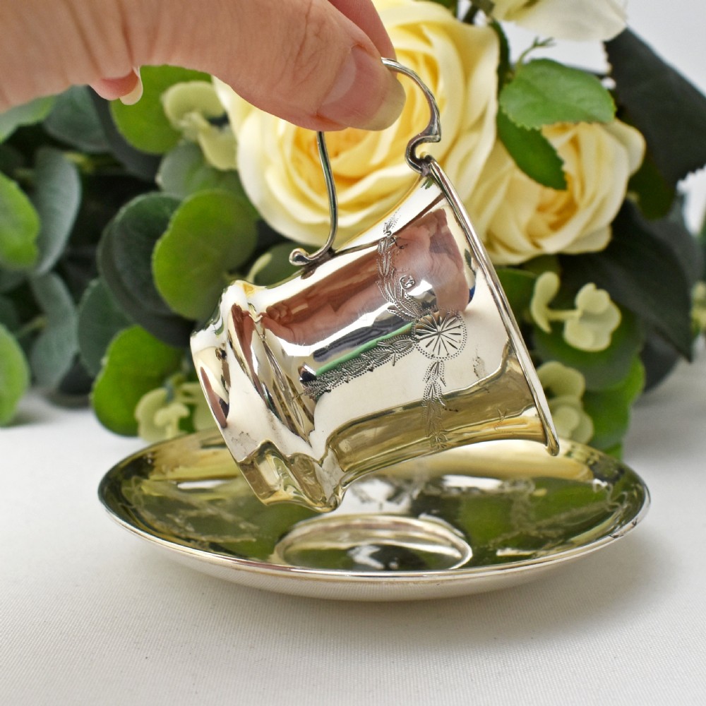 An antique sterling silver cup and saucer set decorated with hand-engraved swag and bow motifs. View VII
