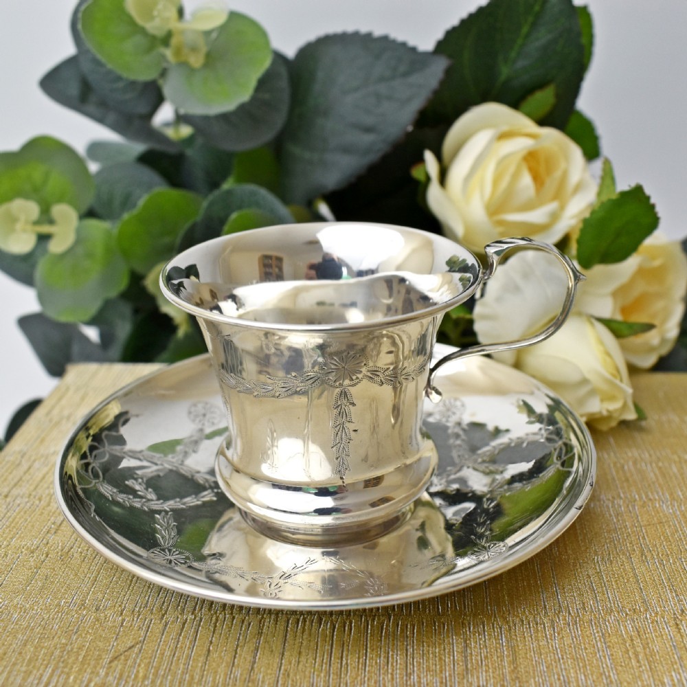 An antique sterling silver cup and saucer set decorated with hand-engraved swag and bow motifs. View VIII