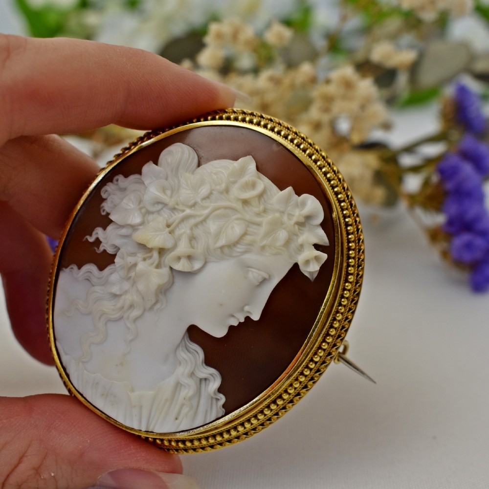 An oval Victorian cameo brooch featuring a white carved relief profile of Goddess Flora set within an 18ct gold frame with a twisted wire border. View V