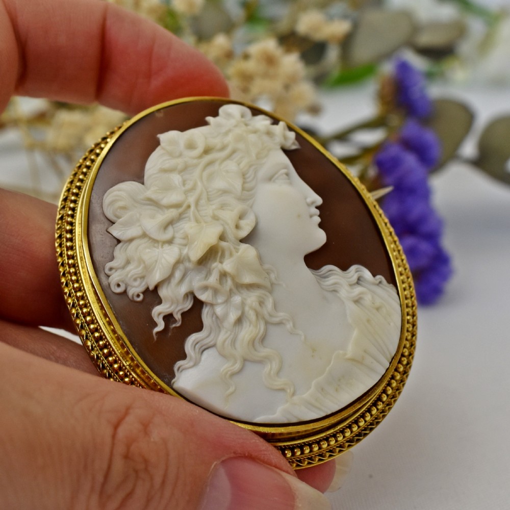 An oval Victorian cameo brooch featuring a white carved relief profile of Goddess Flora set within an 18ct gold frame with a twisted wire border. View VI
