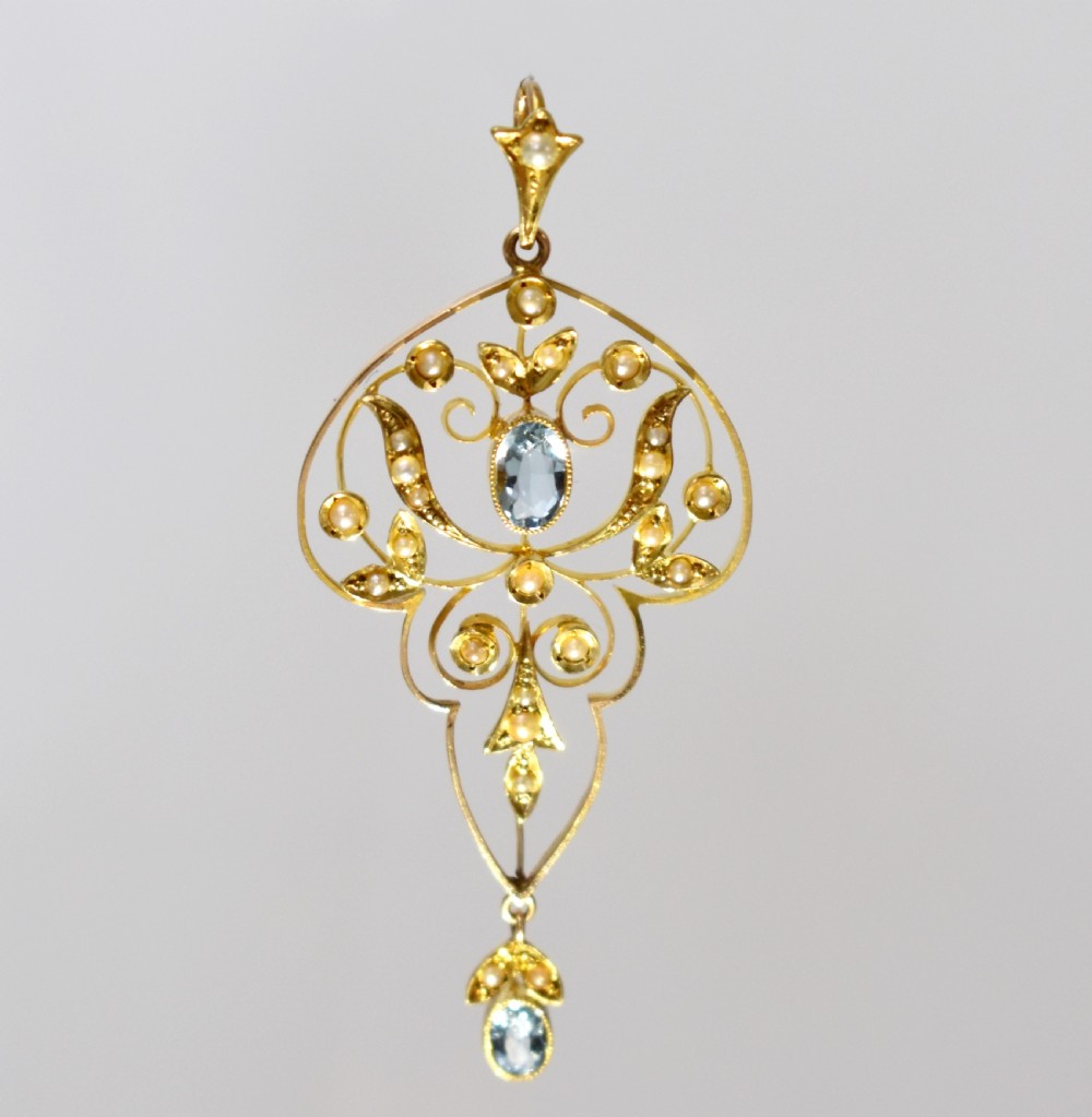 An openwork 15ct gold Art Nouveau pendant featuring intricate leaf motifs, set with seed pearls, a central oval aquamarine, and a suspended aquamarine drop. View II