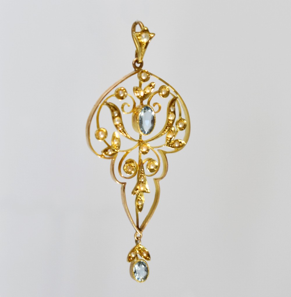 An openwork 15ct gold Art Nouveau pendant featuring intricate leaf motifs, set with seed pearls, a central oval aquamarine, and a suspended aquamarine drop. View III