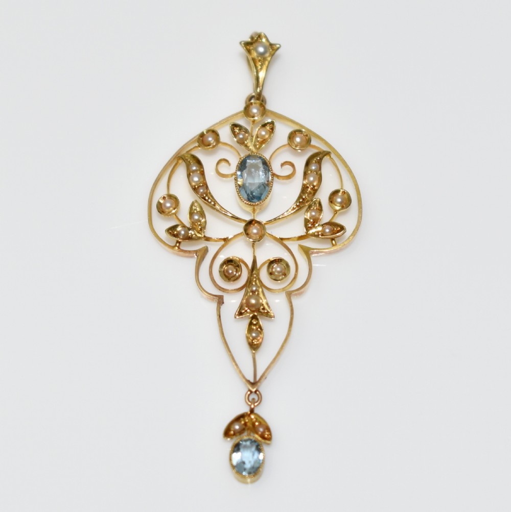 An openwork 15ct gold Art Nouveau pendant featuring intricate leaf motifs, set with seed pearls, a central oval aquamarine, and a suspended aquamarine drop. View VII