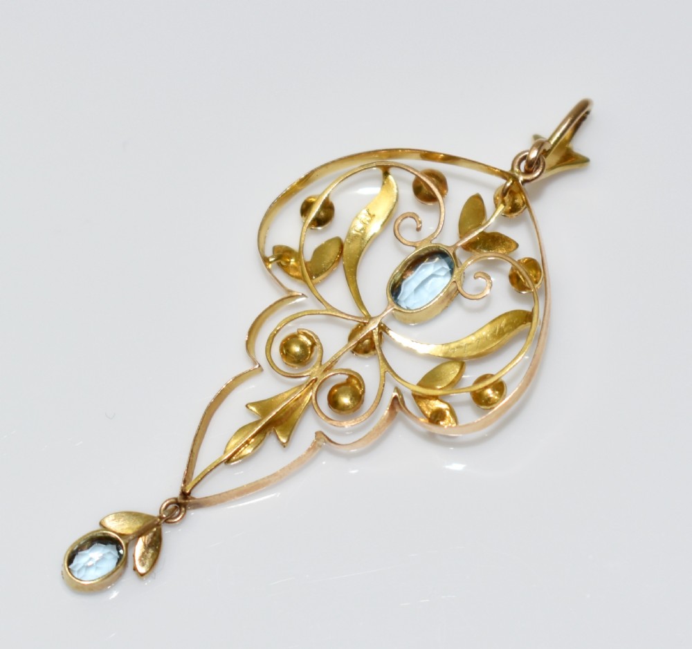 An openwork 15ct gold Art Nouveau pendant featuring intricate leaf motifs, set with seed pearls, a central oval aquamarine, and a suspended aquamarine drop. View XI