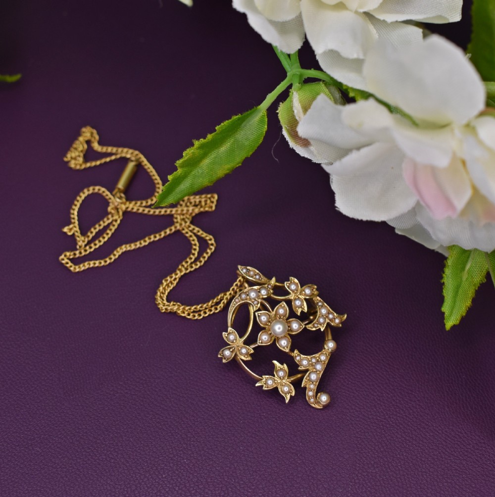 An Edwardian 15ct yellow gold floral brooch pendant featuring openwork scrollwork set with seed pearls. View II