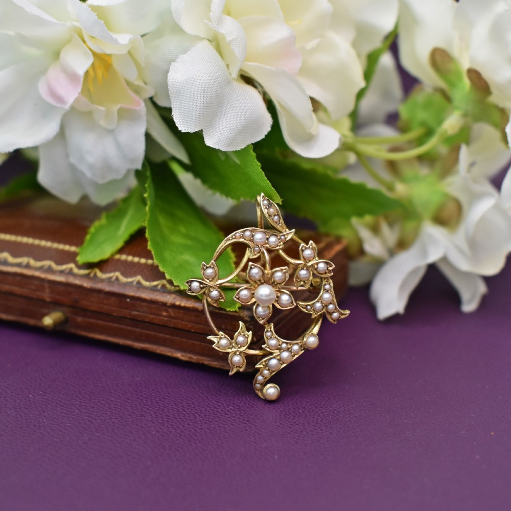 An Edwardian 15ct yellow gold floral brooch pendant featuring openwork scrollwork set with seed pearls. View V