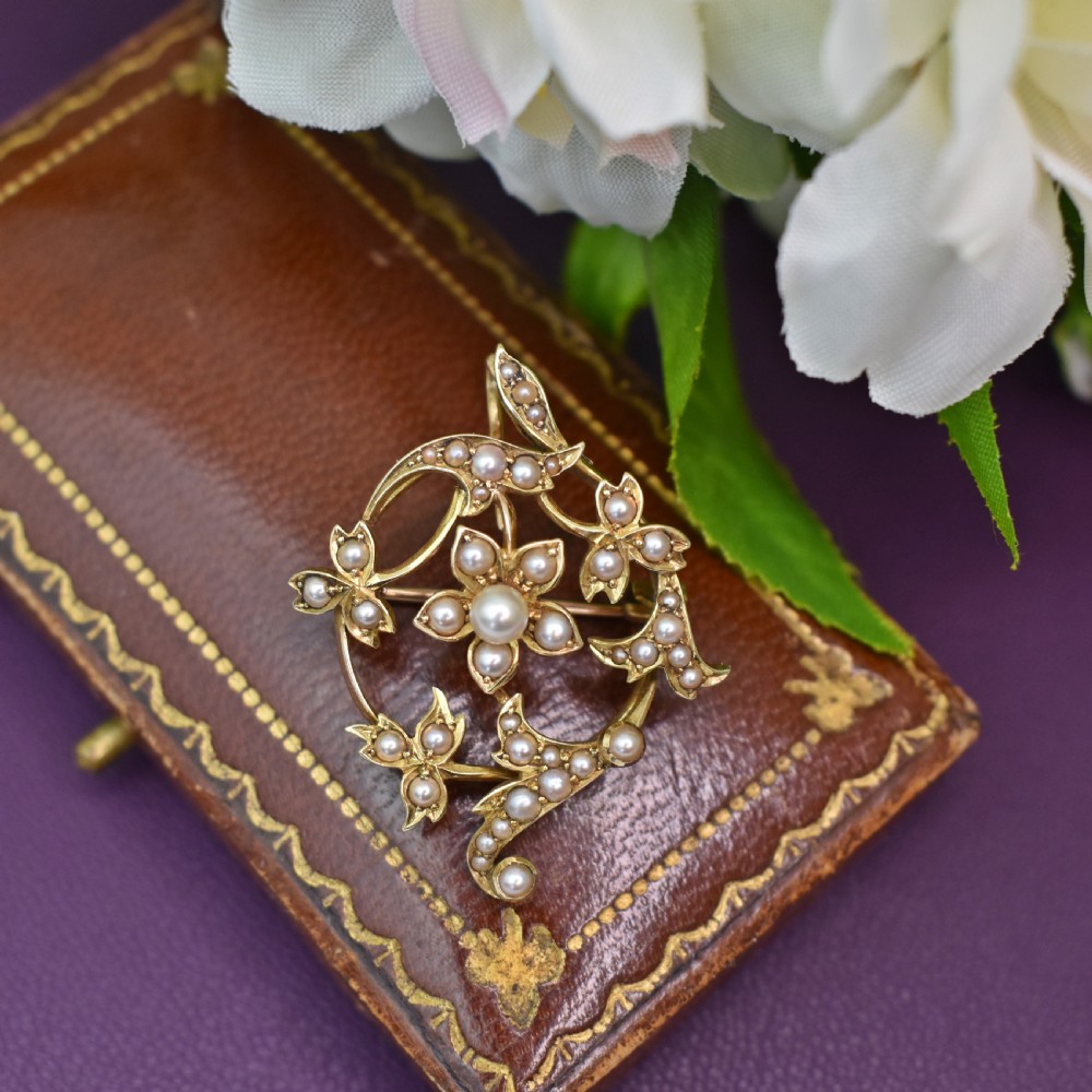An Edwardian 15ct yellow gold floral brooch pendant featuring openwork scrollwork set with seed pearls. View VI