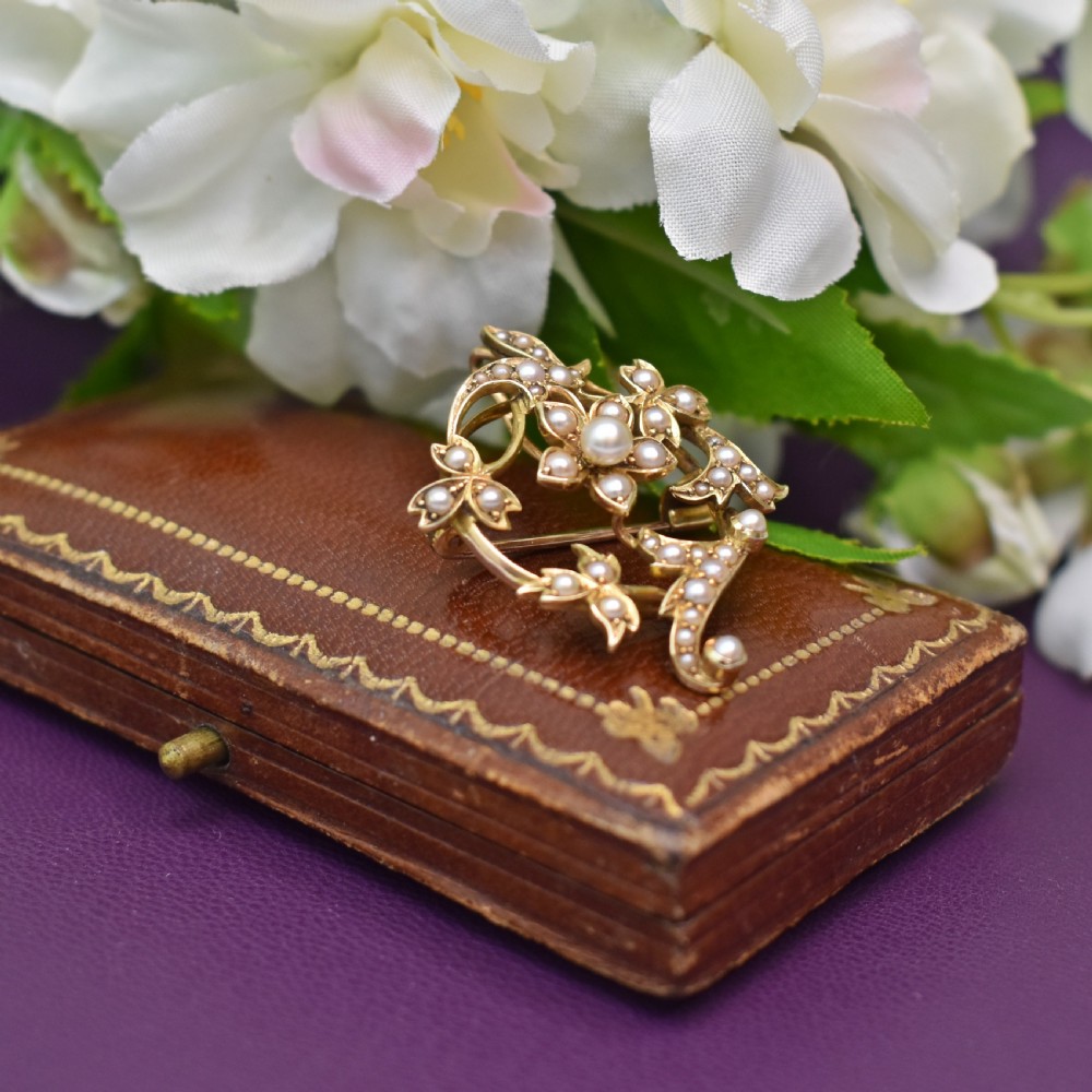 An Edwardian 15ct yellow gold floral brooch pendant featuring openwork scrollwork set with seed pearls. View VII