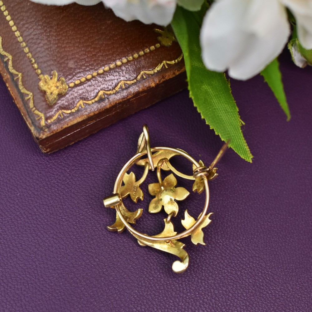 An Edwardian 15ct yellow gold floral brooch pendant featuring openwork scrollwork set with seed pearls. View VIII